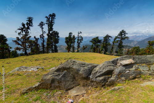 Huge rock on Bugyal, alpine pasture lands, or meadows, in higher elevation range of Himalayas in Uttarakhand, called nature’s own gardens. View of Himalayas on Trekking route to Tunganath. photo