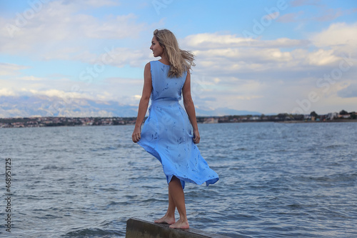 Beautiful blonde woman posing on an empty sea beach photo