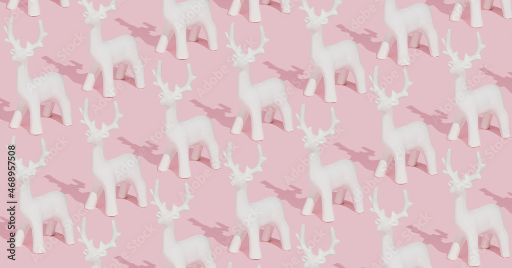 Creative pastel pink winter pattern made with white reindeer ornaments on pink background. Trendy Christmas composition.