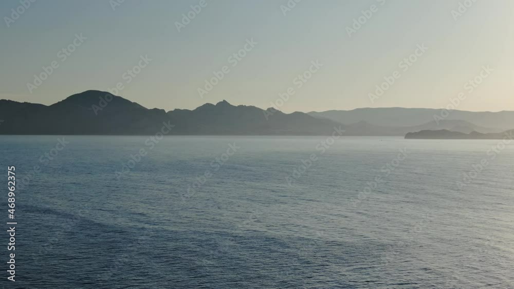 Aerial view of the majestic seascape at sunset with two women silhouettes doing yoga exercises in the sun Aerial view of the majestic seascape at sunset with two women silhouettes doing yoga exercises in the sun