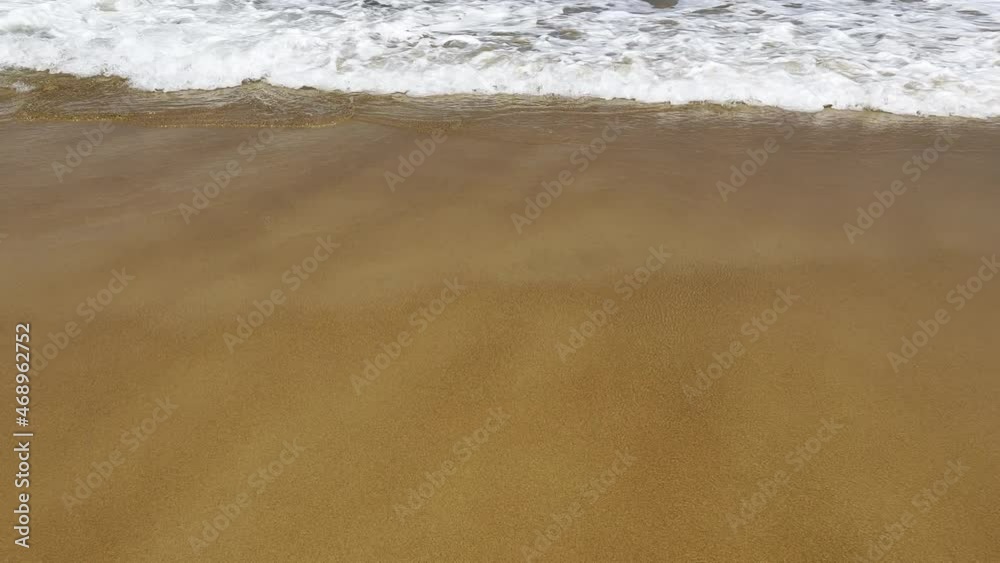 Beautiful landscape ocean waves gently moving ashore onto the beach with an unusual intersecting pattern caused by wave refraction around a tiny rocky island further out to seen. Beautiful landscape ocean waves gently moving ashore onto the beach with an unusual intersecting pattern caused by wave refraction around a tiny rocky island further out to seen.