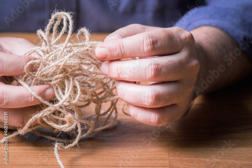 Closeup man try to fix the problem of tangled jute rope