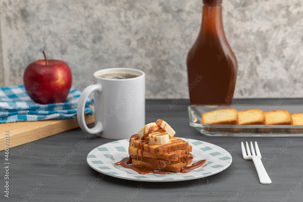 Breakfast of toasted bread with cajeta and banana accompanied by a cup of coffee and apple
