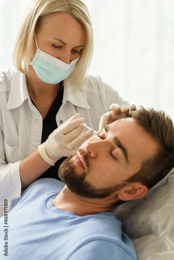 Female doctor and male client during filler injections in clinic Female doctor and male client during filler injections in clinic