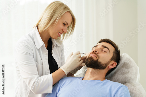Female doctor and male client during filler injections in clinic