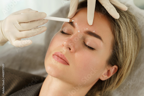 Fotografia Doctor making marks on client's face before filler injection