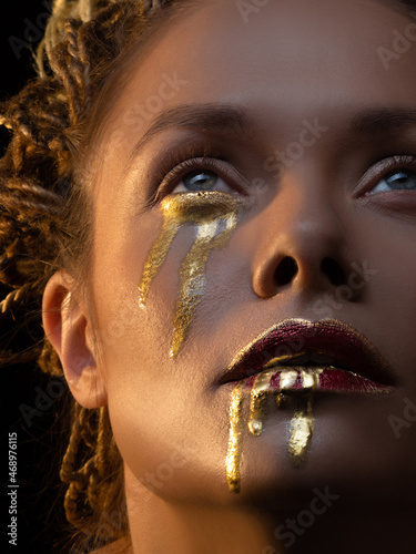 Fotografie Gold on the skin, face art and creative makeup, gold as tears and blood on the f