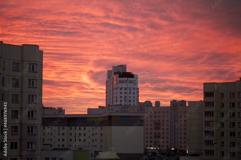 Dawn in the city. Multi-storey buildings and the sky in red and blue are visible.