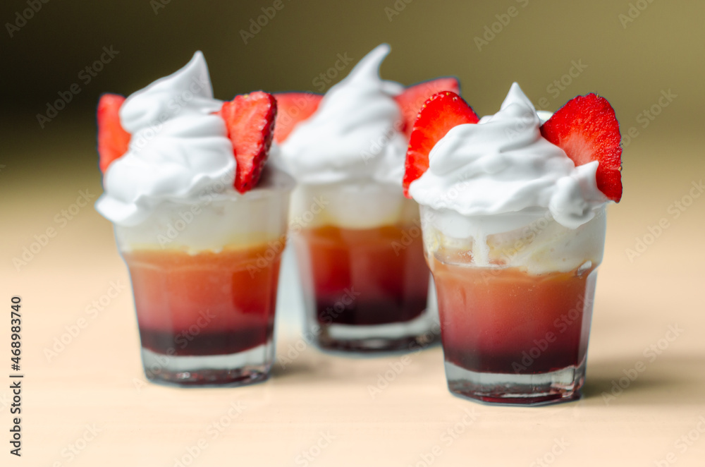 Colorful layered shots of drinks based on vodka, grenadine and orange juice decorated with whipped cream and pieces of strawberry in the shape of bunny ears Colorful layered shots of drinks based on vodka, grenadine and orange juice decorated with whipped cream and pieces of strawberry in the shape of bunny ears