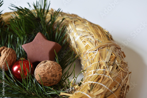 strohkranz mit Nüssen, Christbaumkugel in Rot, Reisig in Grün und Keramikstern in Braun vor Weißem Hintergrund für Weichnachten, Advent, Deko für Weihnachtsfest photo