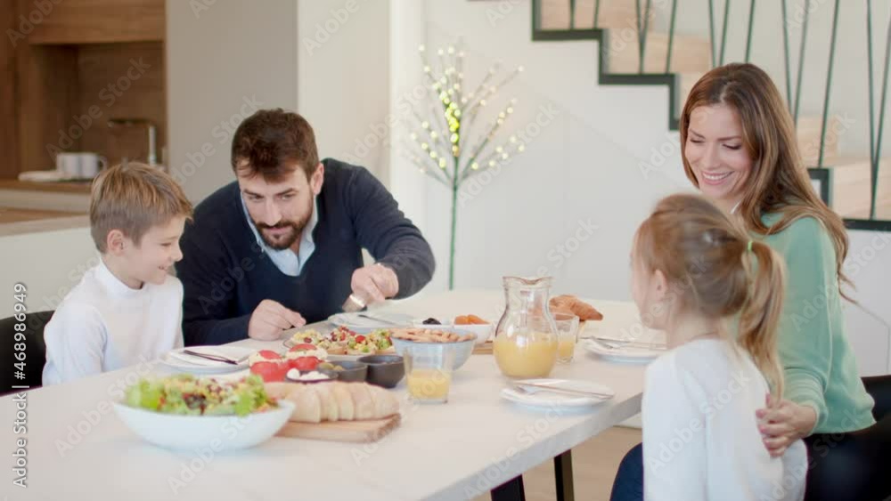 Young happy family talking while having breakfast at dining table at apartment Young happy family talking while having breakfast at dining table at apartment