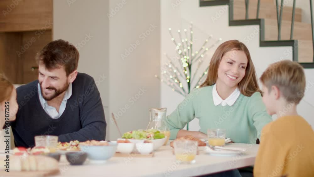 Young happy family talking while having breakfast at dining table at apartment Young happy family talking while having breakfast at dining table at apartment