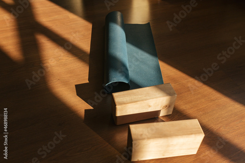 Fototapeta Naklejka Na Ścianę i Meble -  Closeup of two wooden yoga blocks and blue yoga mat on the wooden floor.