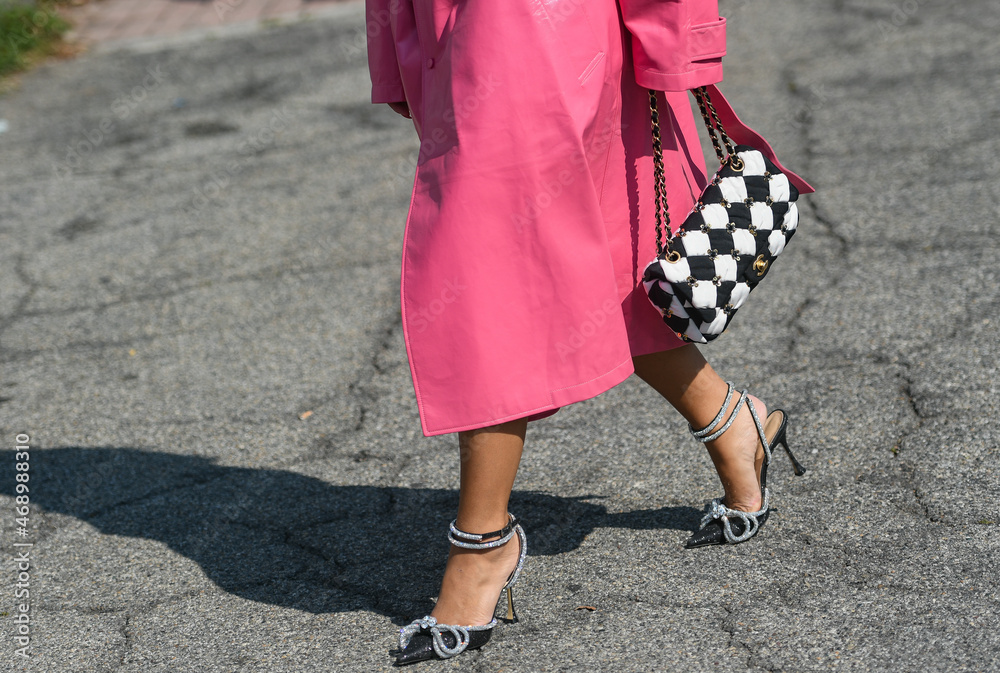 Milan, Italy - September 24, 2021: Street style outfit, fashionable woman  wearing pink long coat, a black and white checkered handbag from Chanel,  black shoes with silver knotted rhinestones Stock Photo