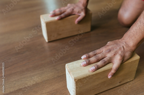 Close-up of a young man's hand holding wooden blocks for yoga and fitness.