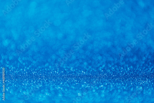 Abstract blurred blue magic glitter background with copy space. Empty festive shiny backdrop with bokeh.