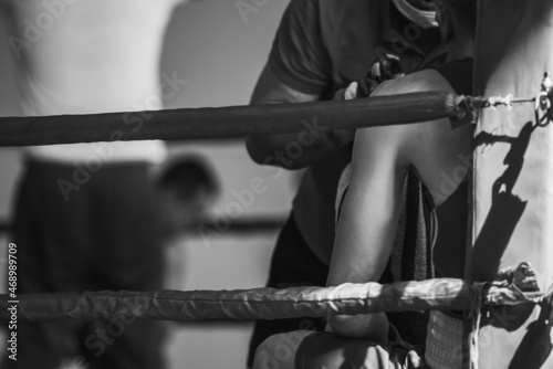 The corner of the boxing ring. The boxer rests between rounds. Retro style black and white background image with shallow depth of field. Sharpness on the athlete in the corner of the ring.