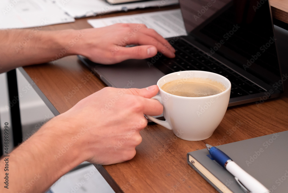A cup of coffee whilst working at the office - Cup of coffee whilst person types A cup of coffee whilst working at the office - Cup of coffee whilst person types