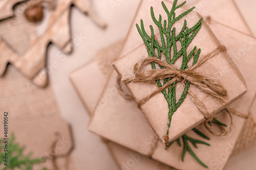 Festive decoration of gifts in eco-style.Gift boxes are wrapped in craft paper,tied with cotton thread,decorated with thuja leaves and burlap,close-up.Christmas,New Year and eco-friendly concept.