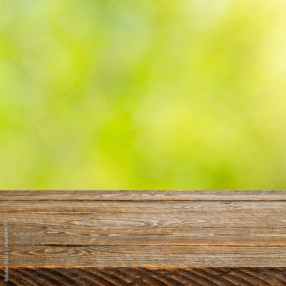 Background with blurred green leaves and empty wooden planks in the foreground. Background with blurred green leaves and empty wooden planks in the foreground.