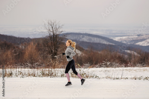 Fit sportswoman jogging in snow in the nature at winter. Healthy lifestyle, cardio exercises, winter fitness