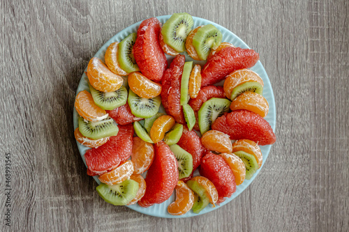 Vegan Christmas food. peeled fruits on a plate. kiwi, grapefruit, tangerine
