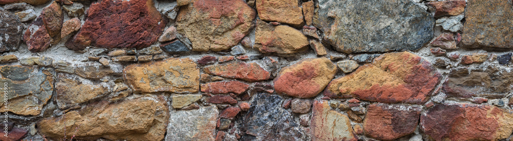 Old stone wall surface in abandoned building. Rough multicolored natural stone, texture panorama Old stone wall surface in abandoned building. Rough multicolored natural stone, texture panorama