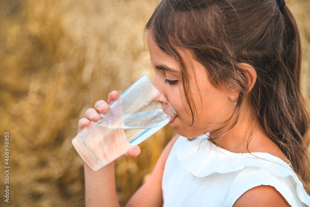 The child drinks water from a glass. Selective focus. The child drinks water from a glass. Selective focus.