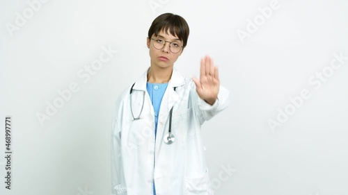 Young woman with nurse uniform doing stop sign over isolated background