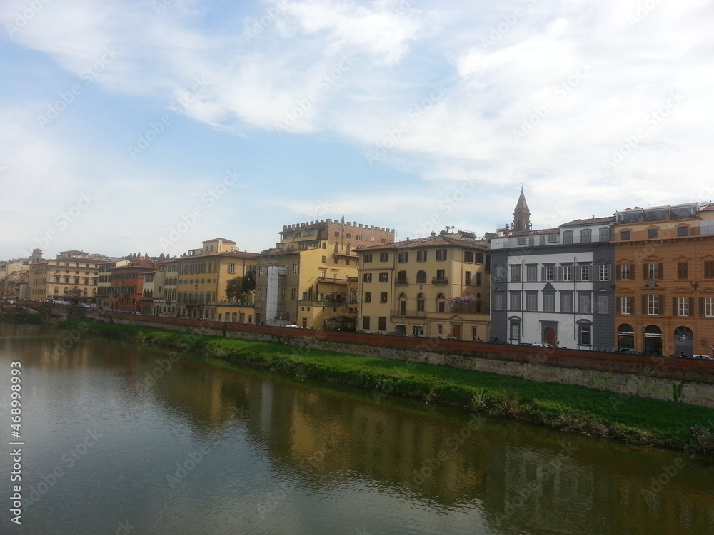 Florence, la capitale de la Toscane, le fleuve Arno longeant la ville, ses maisons colorés en jaune ou orange, avec pont au fond, balade tranquille aquatique et communale, ciel nuageux