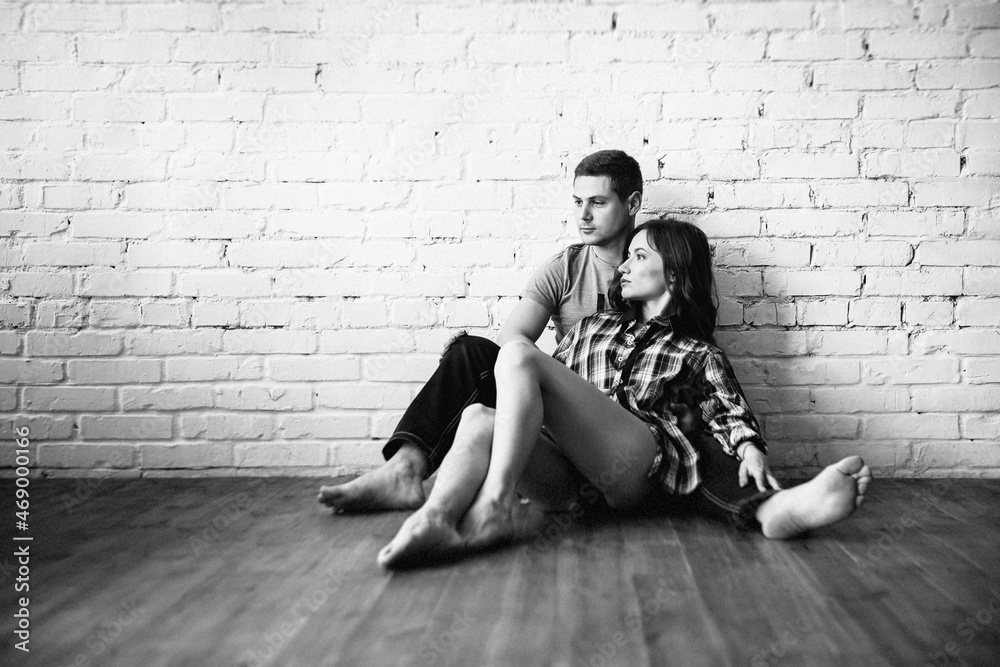 guy and girl sit on the floor near a white wall