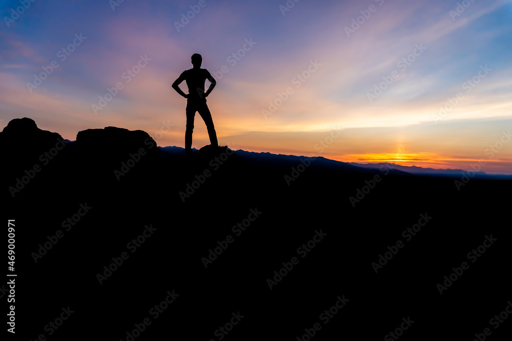 Silhouette of a winner man standing on a mountain. The concept of sports and active life.