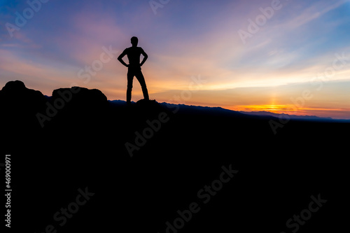 Silhouette of a winner man standing on a mountain. The concept of sports and active life.