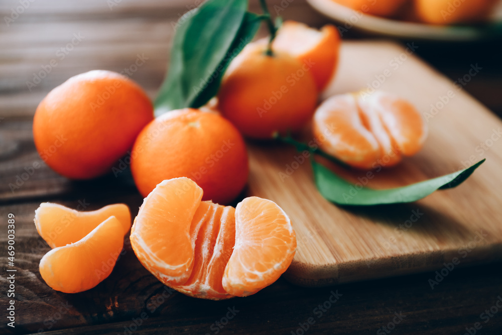 Fresh clementines with leaves on wooden table, close up Fresh clementines with leaves on wooden table, close up