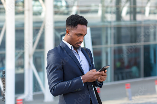 african businessman traveling near airport with suitcase calling taxi using mobile app