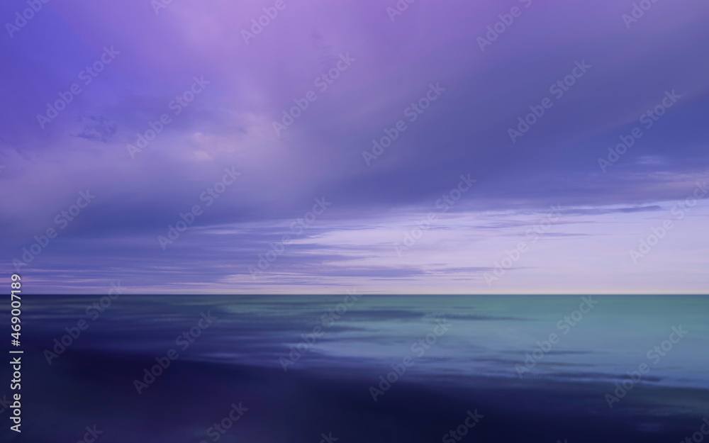 Dramatic cloudscape with purple, pink, and blue storm clouds gathering over the blue seawater.