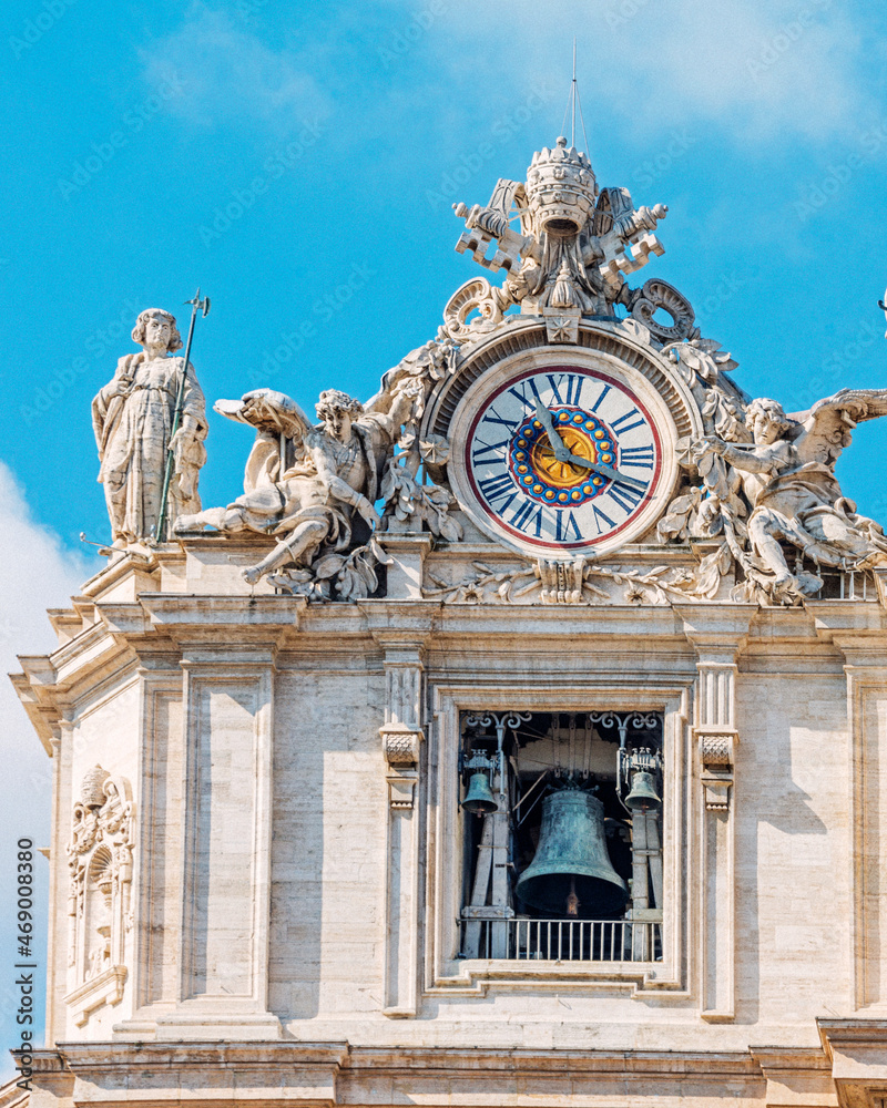 Bernini's tower clock in the Colonnade in St. Peter’s Square. The saints and martyrs belonging to the early Church can be found over the northern colonnade’s balustrade. Vatican City, 