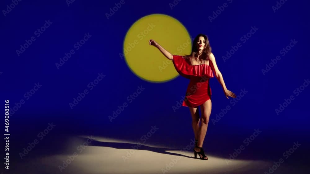 A beautiful Latino Woman dances in a red dress against a sunset background