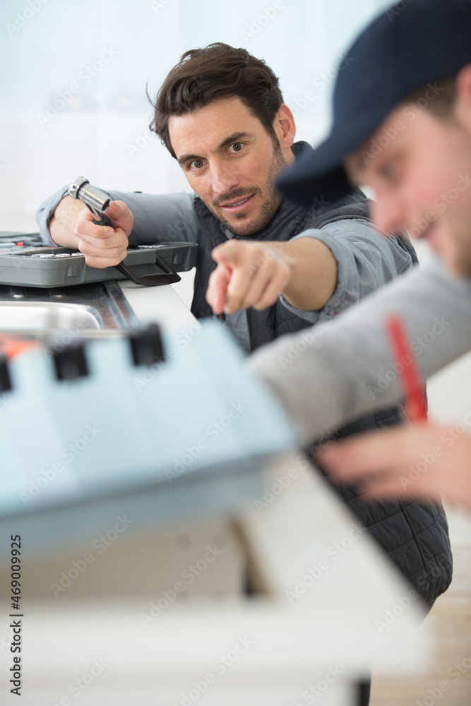 worker installing kitchen with apprentice worker installing kitchen with apprentice