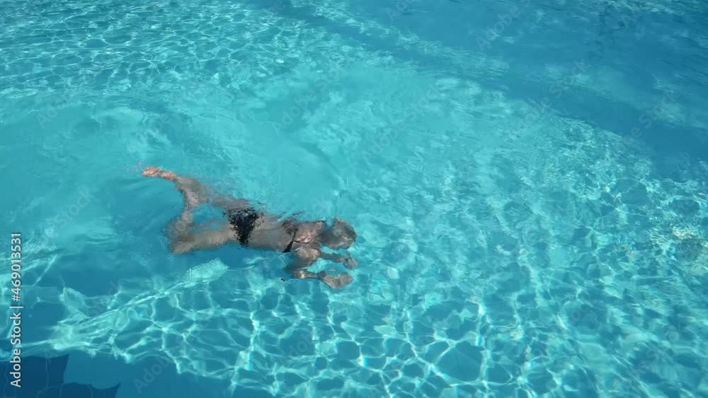 Active young woman diving in pool and splashing water. Lady relaxing on tropical resort. Active young woman diving in pool and splashing water. Lady relaxing on tropical resort.