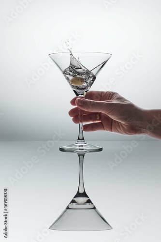 Female hand taking a cocktail glass with martini splash.