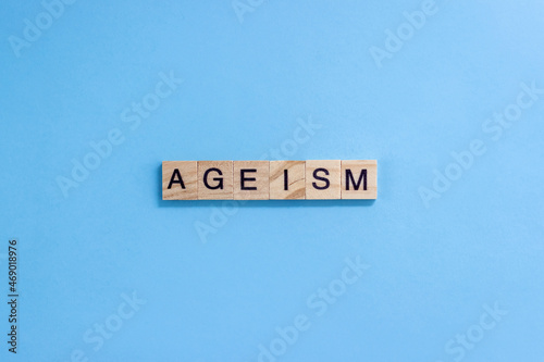 The word Ageism. Wooden blocks with letters on a blue background. Age discrimination concept. Copy space.