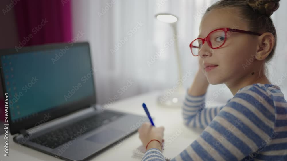 teenage girl doing homework at the laptop, looking at the screen and laughing. teenage girl doing homework at the laptop, looking at the screen and laughing.