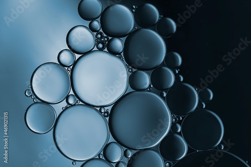 Closeup of water and oil droplets on dark blue background. 