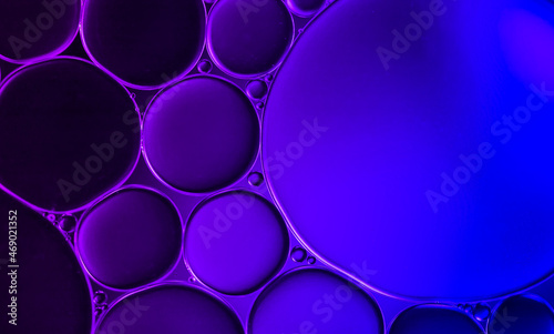 Oil droplets on water surface to created bubble and an art image on purple background.