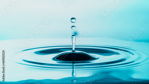 Water droplet splash and make perfect ripples on water surface background.