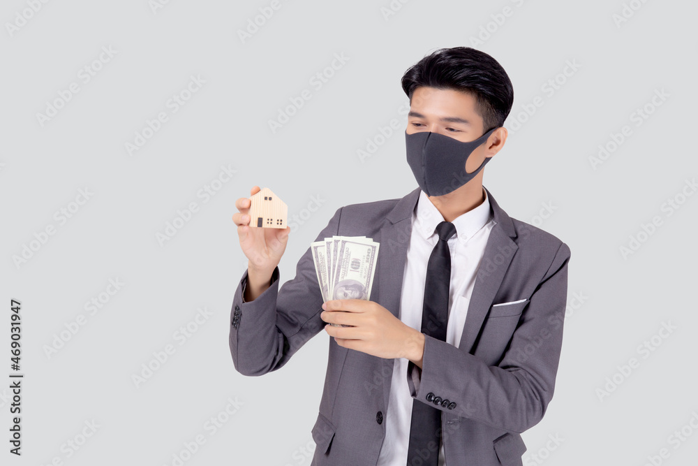 Young asian businessman in face mask holding money dollar and home isolated on white background, pandemic and crisis of economic, business man and investment property during disease covid-19. Young asian businessman in face mask holding money dollar and home isolated on white background, pandemic and crisis of economic, business man and investment property during disease covid-19.