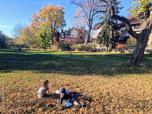 A mother and daughter lying in a pile of autumn leaves surrounded by beautiful trees and homes, on a beautiful fall day in the Glebe, in Ottawa, Ontario Canada photo