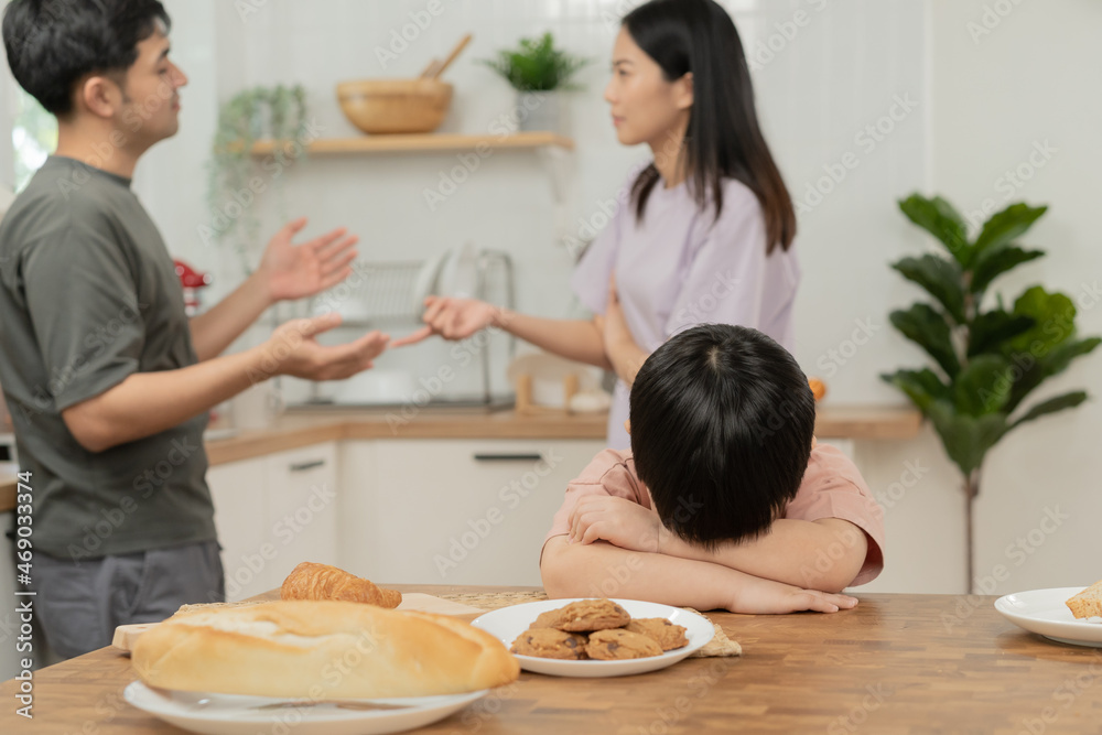 Little asian sad boy, unhappy while parents fighting, kid son not listen to shouting noise while mom and dad arguing, quarrel behind. Family suffering, stressed. Violence and divorce couple concept. Little asian sad boy, unhappy while parents fighting, kid son not listen to shouting noise while mom and dad arguing, quarrel behind. Family suffering, stressed. Violence and divorce couple concept.