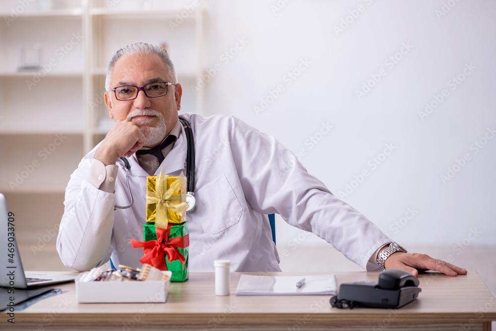 Old male doctor celebrating Christmas at the hospital Old male doctor celebrating Christmas at the hospital